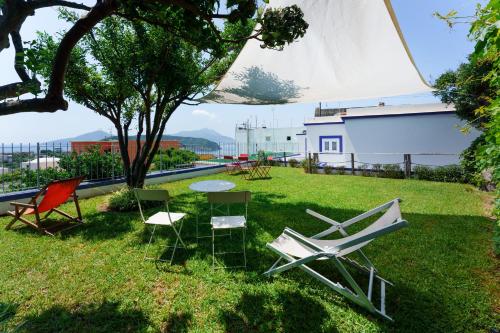 a group of chairs and a table in the grass at Poseidonia Rooms in Procida