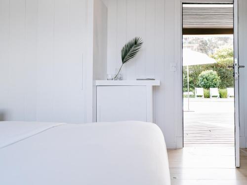 a white bedroom with a bed and a plant on a counter at Casa Flor in Punta del Este