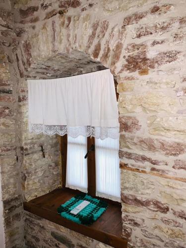 a window in a stone wall with a white curtain at Guest House and Hostel VAL-MAR in Gjirokastër