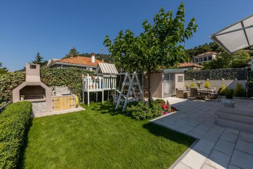 a backyard with a garden with a tree and a ladder at Villa KaTess with heated pool in Split