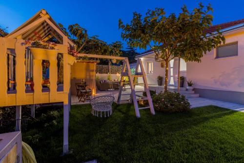 a backyard with a swing and a tree at Villa KaTess with heated pool in Split