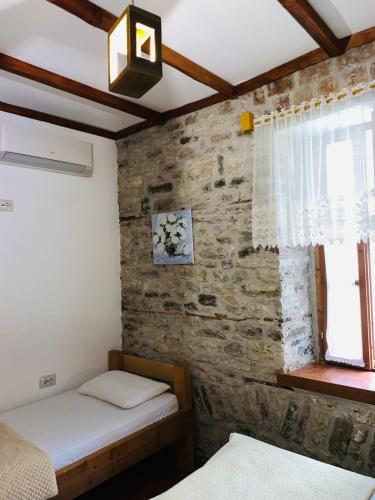 a bedroom with two beds and a stone wall at Guest House and Hostel VAL-MAR in Gjirokastër
