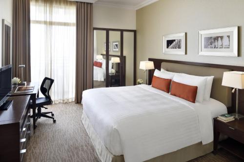 Marriott Executive Apartments Riyadh, Convention Center في الرياض: غرفة في الفندق مع سرير أبيض كبير ومكتب