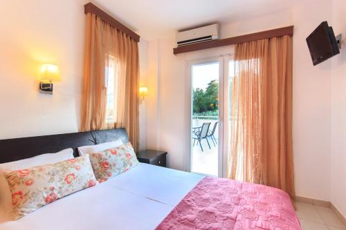 a bedroom with a bed and a window with a patio at Rani Apartments in Chrysi Ammoudia