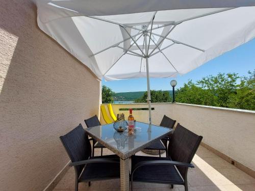 a table and chairs with an umbrella on a balcony at Apartment Marino in Čižići