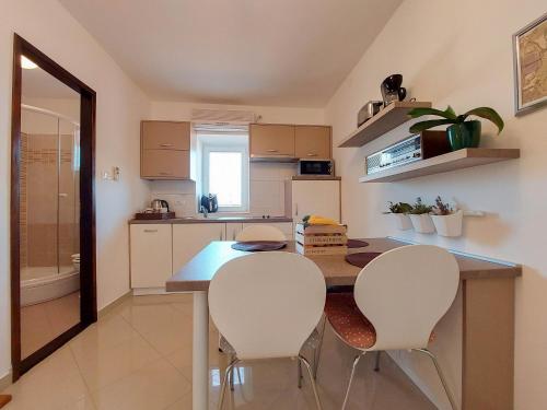 a kitchen with a table and two white chairs at Apartment Marino in Čižići