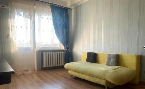 ein Wohnzimmer mit einem gelben Sofa und einem Fenster in der Unterkunft Apartment in city center in Kiew