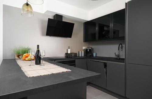 a kitchen with black cabinets and a table with a bottle of wine at House Luxury Konforta in Brodarica