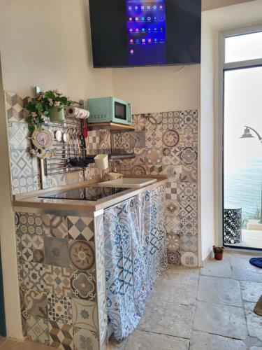 a kitchen with a sink and a tiled wall at Nonna Libera Vista Mare in Rodi Garganico