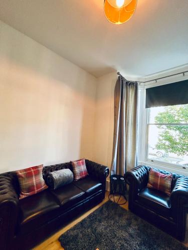 a living room with two leather couches and a window at 1 bedroom apartment in Shepherds Bush, London in London