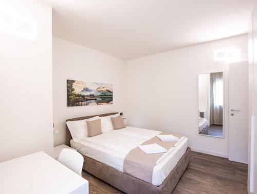 Habitación blanca con cama y espejo en BORGO VERTICALE Luxury Apartments, en Feltre