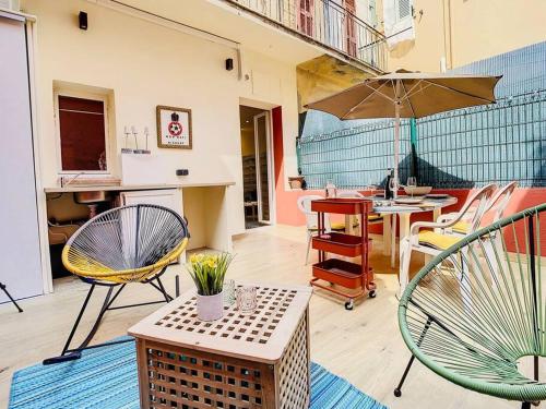 un patio avec des chaises et une table avec un parasol dans l'établissement Appartement Terrasse Proche Port et Plages de Nice, à Nice