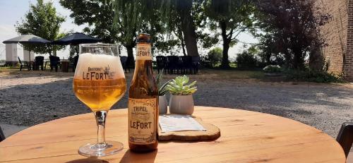 una botella de cerveza y un vaso sobre una mesa en Varlet Farm en Poelkapelle