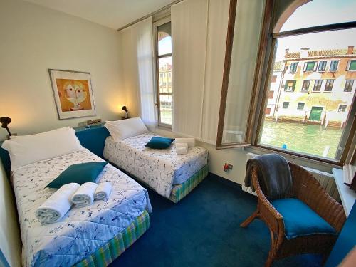 a room with two beds and a chair and a window at Al Ponte Lungo - Giudecca in Venice