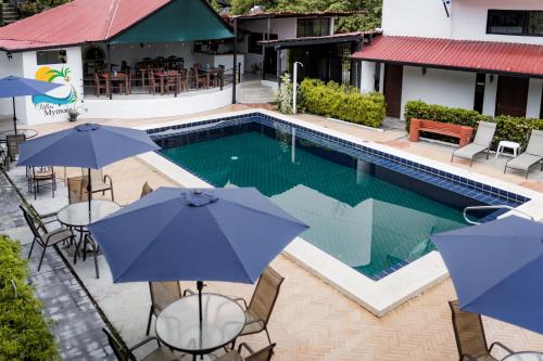 a pool with chairs and umbrellas next to a building at Condiminium Villas Mymosa in Manuel Antonio