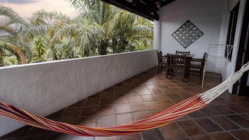 a hammock on the balcony of a house with palm trees at Condiminium Villas Mymosa in Manuel Antonio