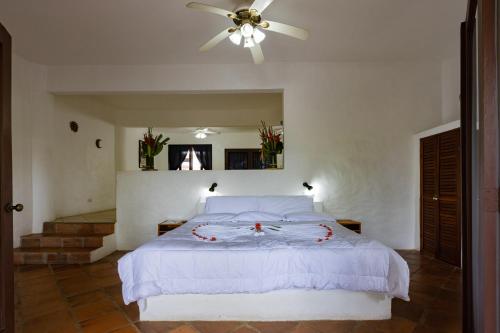 a bedroom with a white bed with a ceiling fan at Condiminium Villas Mymosa in Manuel Antonio