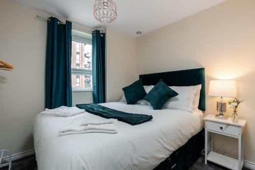 a bedroom with a large white bed with green curtains at Stylish 2 Bed Manchester Flat in Manchester