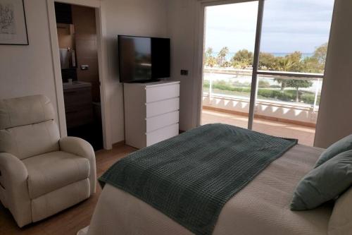 1 dormitorio con 1 cama, 1 silla y TV en Villa de lujo frente al mar, en Barrio-Mar