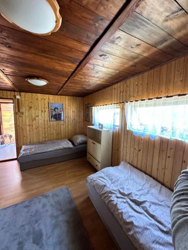 1 dormitorio con 2 camas y techo de madera en Chata U Řeky, 