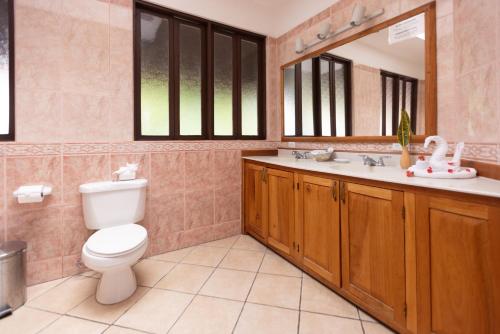 a bathroom with a toilet and a sink and a mirror at Condiminium Villas Mymosa in Manuel Antonio