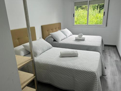 una habitación con dos camas y una ventana en O Fogar De Elisa, en Redondela