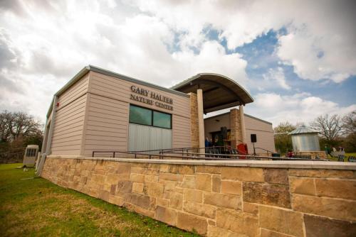 a building with a stone wall in front of it at Holiday Inn & Suites College Station-Aggieland by IHG in College Station