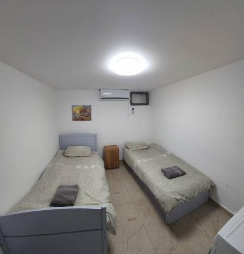 Habitación con 2 camas y una luz en la pared. en The Premier Apartment In RBS A, en Bet Shemesh
