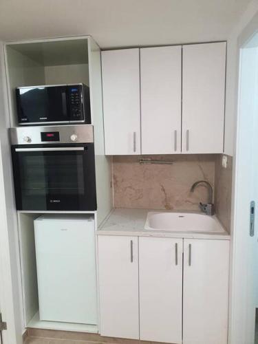 cocina con armarios blancos, microondas y fregadero en The Premier Apartment In RBS A, en Bet Shemesh