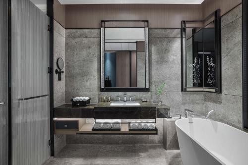 a bathroom with a tub and a sink and a mirror at JW Marriott Hotel Shenzhen Bao'an International Airport in Bao'an