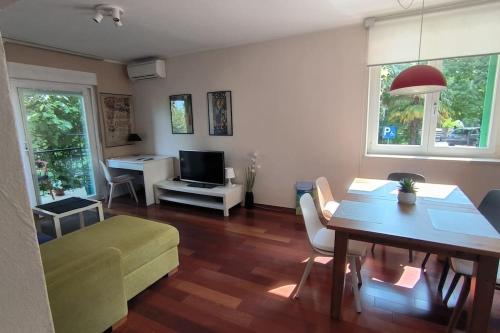 een woonkamer met een tafel, een bank en een televisie bij Apartman Sonja in Lovran