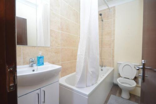ein Badezimmer mit einem Waschbecken, einem WC und einem Duschvorhang in der Unterkunft Lovely 3bedroom Apartment London in London