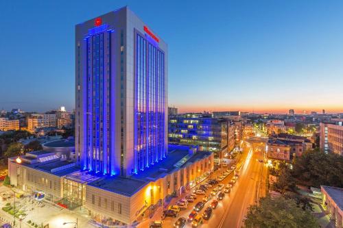 een hoog gebouw met blauwe lichten erop in een stad bij Sheraton Bucharest Hotel in Boekarest