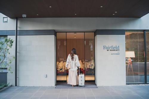 a woman is standing outside of a building holding a suitcase at Fairfield by Marriott Gifu Gujo in Gujo