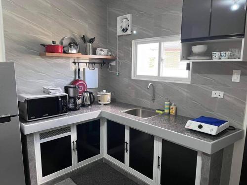 a small kitchen with a sink and a microwave at Sidra Ville Apartment in Balanga