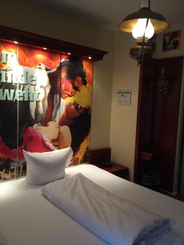 a bed in a room with a poster on the wall at CineHotel Maroni in Zirndorf