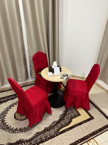 a table with two red chairs and a table with at ضيافة الأمير The Prince Hospitality in Barka