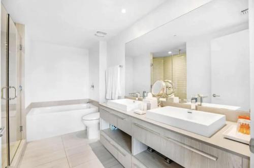 HYDE BEACH HOUSE #2408 THREE-BEDROOM, WATERFRONT, OCEAN AND INTERCOSTAL VIEW, ROOFTOP POOL, 5 MiN WALK TO BEACH في هوليوود: حمام أبيض مع مغسلتين وحوض استحمام ومرحاض