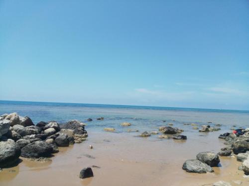 a group of rocks on a beach with the water at Marea affittacamere in Porto Empedocle
