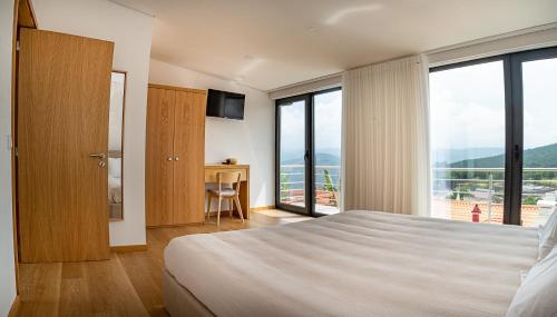 um quarto de hotel com uma cama e uma grande janela em Casa Alto da Massada em Canelas