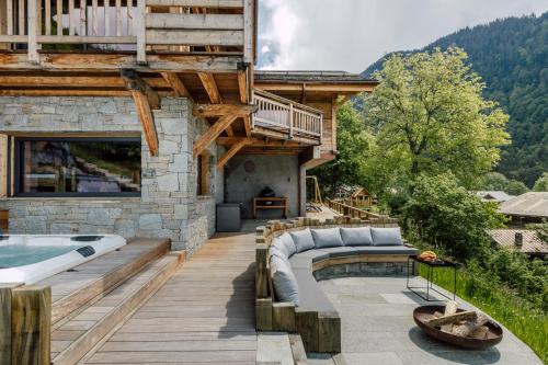 une terrasse avec un bain à remous et une maison dans l'établissement Chalet Grand-Duc, à Montriond