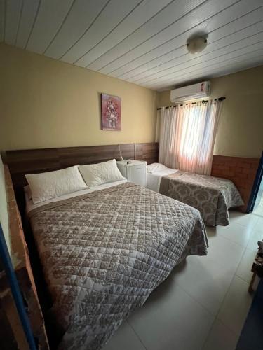 a hotel room with two beds and a window at Pousada São José in Chapada dos Guimarães