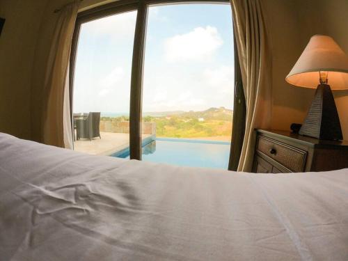 a bedroom with a bed and a window with a view of a pool at Relax Enjoy Upscale Villa Pristine Bay in Roatan