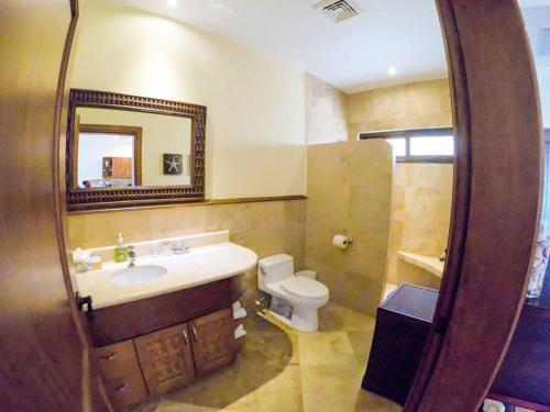 La salle de bains est pourvue d'un lavabo, de toilettes et d'un miroir. dans l'établissement Relax Enjoy Upscale Villa Pristine Bay, à Roatán