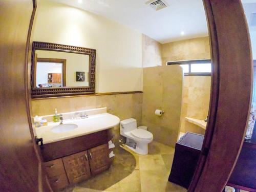 a bathroom with a sink and a toilet and a mirror at Relax Enjoy Upscale Villa Pristine Bay in Roatan