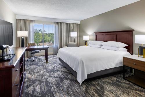 a hotel room with a large bed and a desk and a computer at Sheraton Atlanta Perimeter North in Atlanta