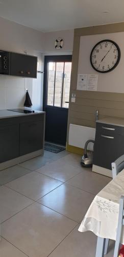 a kitchen with a clock on the wall and a table at Aux Passagers de la baie 2 in Le Crotoy