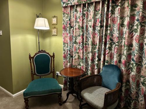 a room with two chairs and a table and a curtain at The George Hotel Easingwold in Easingwold