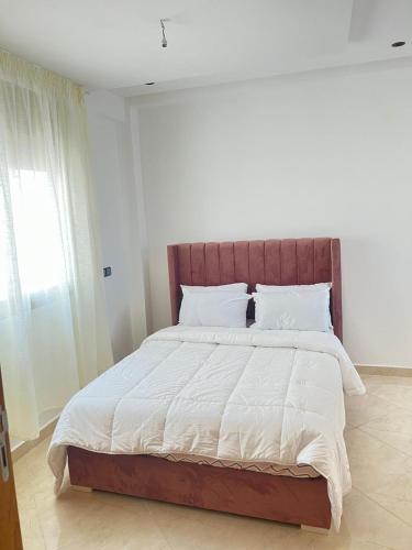 - une chambre avec un grand lit et des draps blancs dans l'établissement Adorable Appartement meublé en plein centre ville, à Kenitra