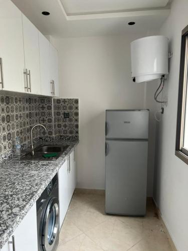 La cuisine est équipée d'un réfrigérateur et d'un évier. dans l'établissement Adorable Appartement meublé en plein centre ville, à Kenitra